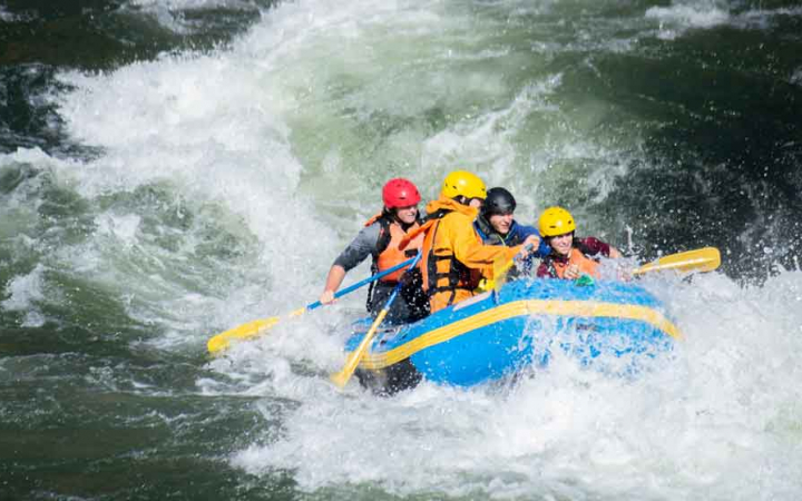 a group of adults navigate whitewater in a raft on an outward bound trip